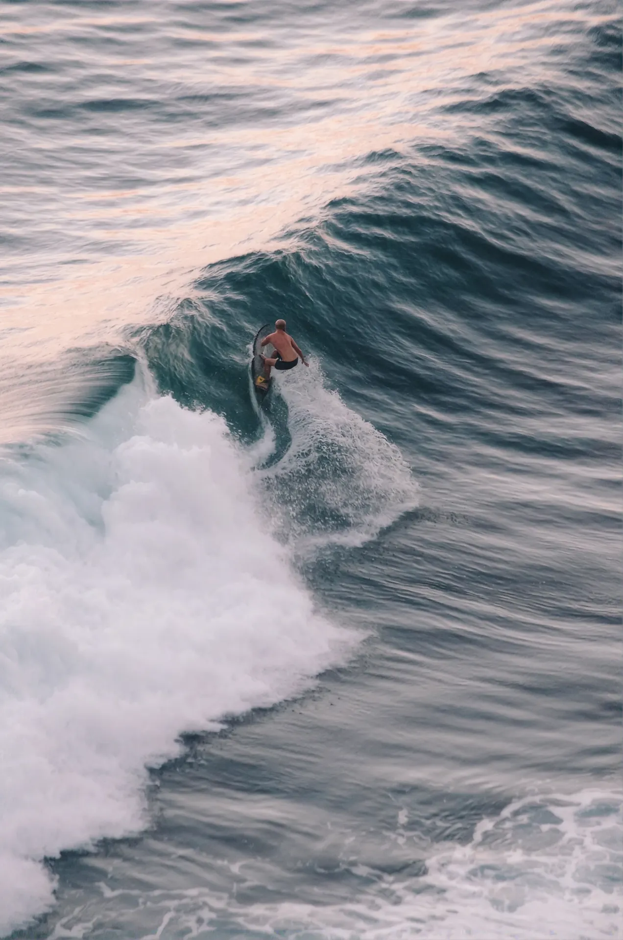 Surfer riding a wave at golden hour